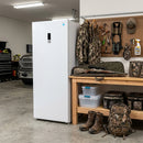 White upright freezer standing in a garage, front view with closed door